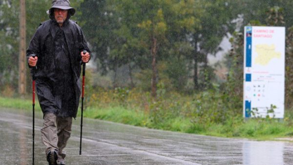 Un peregrino camina bajo la lluvia a su paso por Ponferrada (César Sánchez)