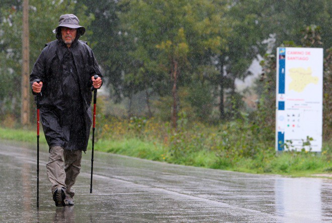 Un peregrino camina bajo la lluvia a su paso por Ponferrada (César Sánchez)